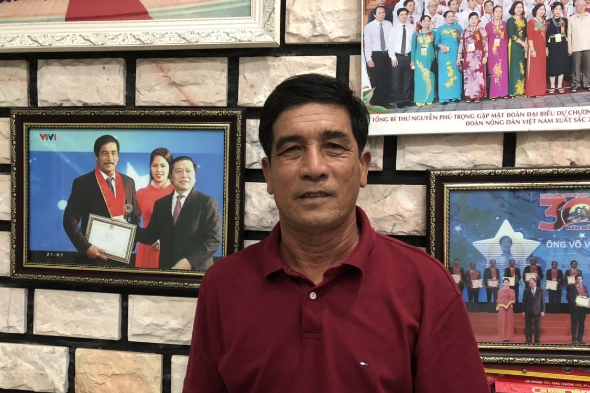 Nông dân Võ Văn Sơn bên những bức ảnh quý được ông treo trang trọng trong nhà