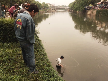 Người dân xuống sông bắt cá.