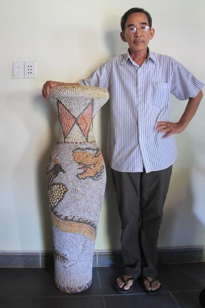 Ông Năm bên chiếc lục bình được ghép từ ốc với hình rồng uốn lượn. Ảnh: Nguyễn Đông