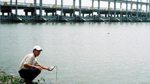 Cán bộ thủy lợi đo độ mặn của nước ở cống đập Ba Lai. (Ảnh: Phan Lữ Hoàng Hà)