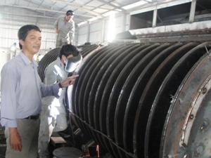 Ông Đặng Lợi đứng bên cạnh thiết bị dây chuyền sản xuất bột cá. (Ảnh: Việt Hùng/Vietnam+)